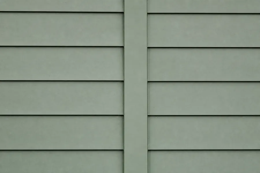 Smooth painted fiber cement lap siding with a completely flat unembossed face, very crisp shadow lines and a slim vertical trim batten at the joint.